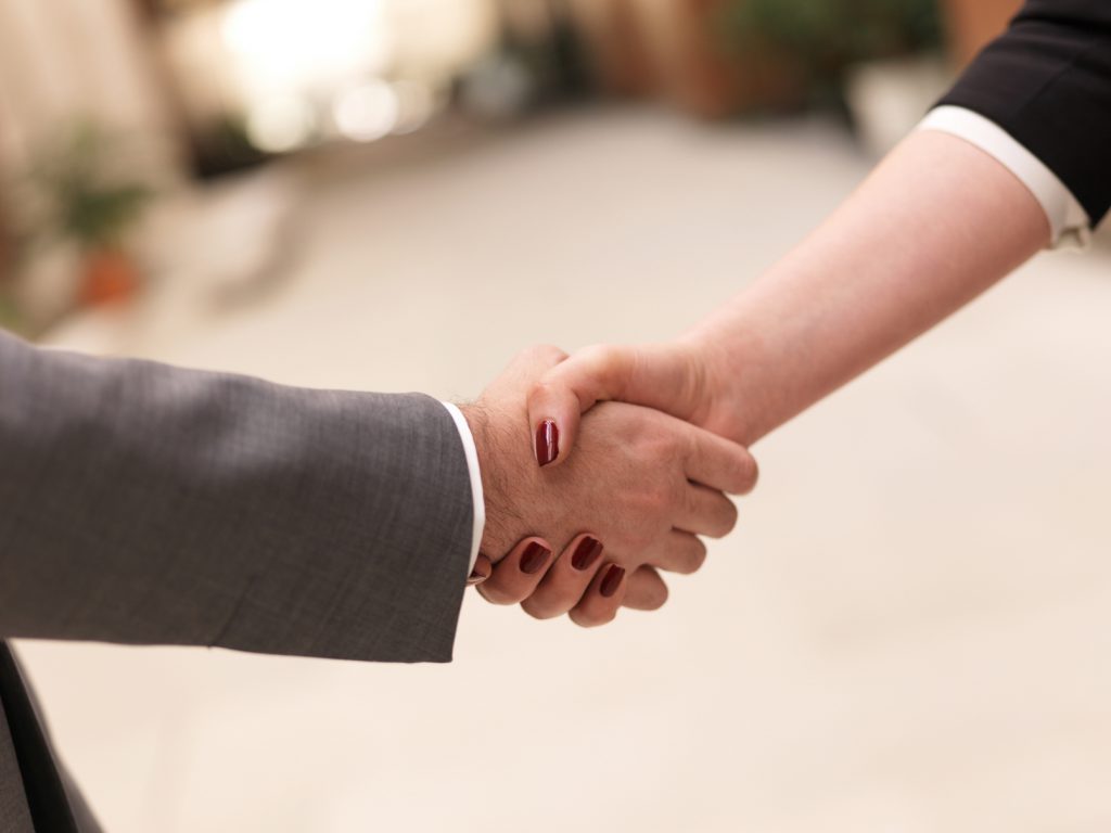 business partners concept with businessman and businesswoman handshake at modern office indoors